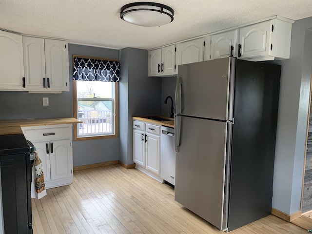 3118 Exeter St, Duluth, MN 55806 - kitchen featuring stainless steel appliances, light wood-style floors, a textured ceiling, white cabinets, and butcher block counters