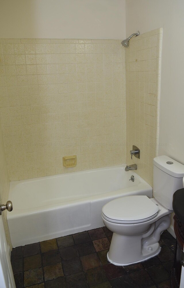 bathroom featuring tiled shower / bath combo and toilet