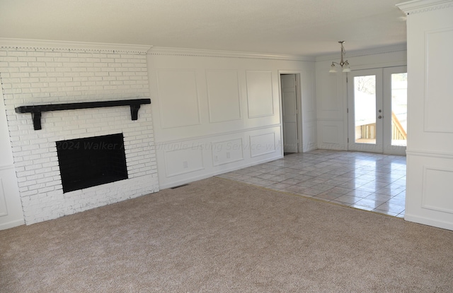 unfurnished living room featuring a fireplace, french doors, light colored carpet, and ornamental molding