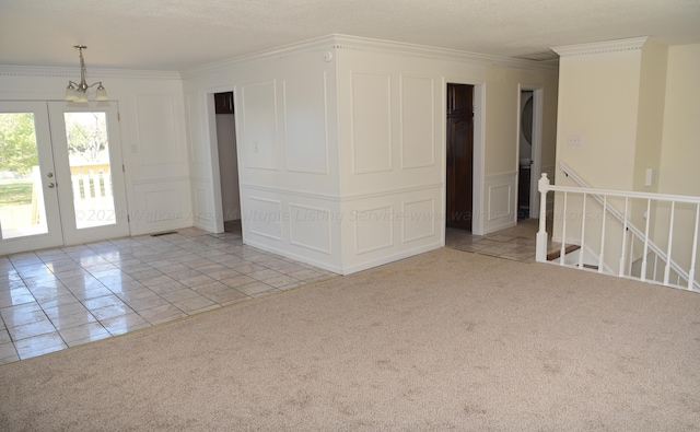 unfurnished room with crown molding, light carpet, french doors, and a chandelier