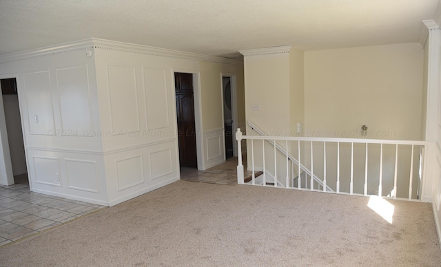 carpeted spare room with a textured ceiling and crown molding