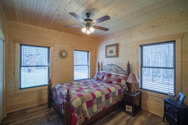 bedroom with dark hardwood / wood-style flooring, wooden walls, and multiple windows