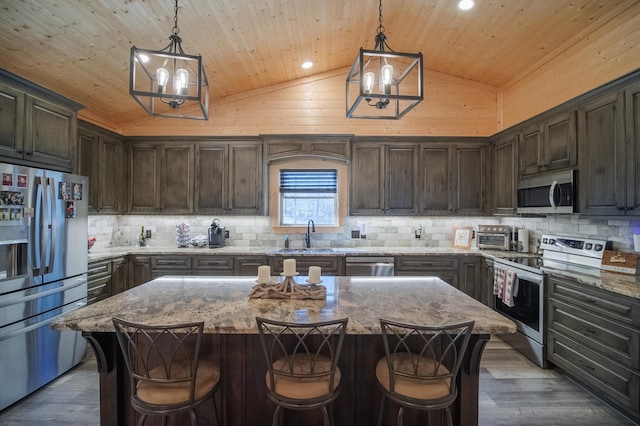 kitchen with hanging light fixtures, appliances with stainless steel finishes, a center island, and dark brown cabinets