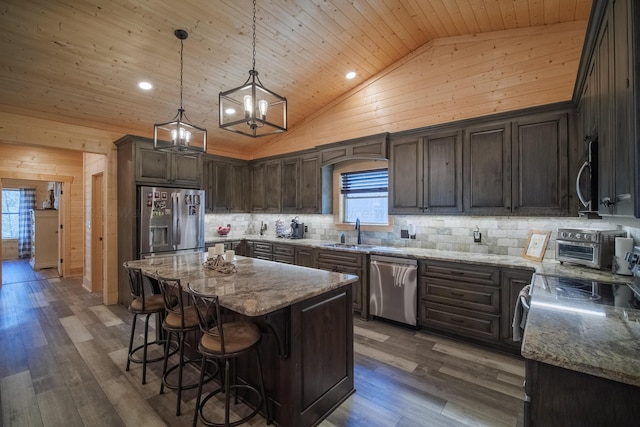 kitchen with stainless steel appliances, dark wood-type flooring, high vaulted ceiling, a kitchen island, and wood walls