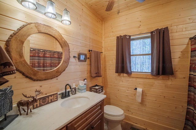 bathroom with wooden walls, vanity, wooden ceiling, and toilet