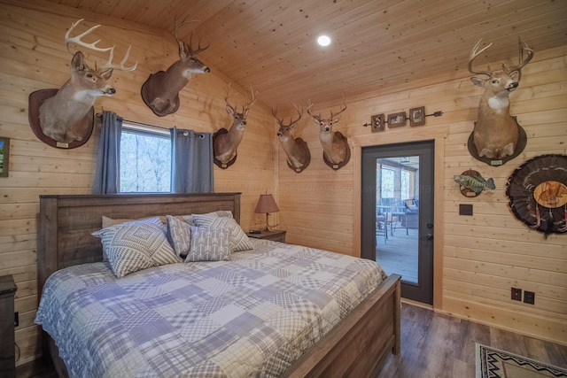 bedroom with dark hardwood / wood-style flooring, lofted ceiling, wooden walls, and multiple windows