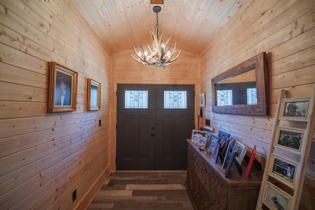 foyer entrance featuring an inviting chandelier, dark hardwood / wood-style floors, vaulted ceiling, and wood walls