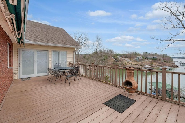 deck with outdoor dining space and a water view