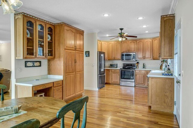 kitchen with glass insert cabinets, stainless steel appliances, light countertops, light wood-type flooring, and a sink