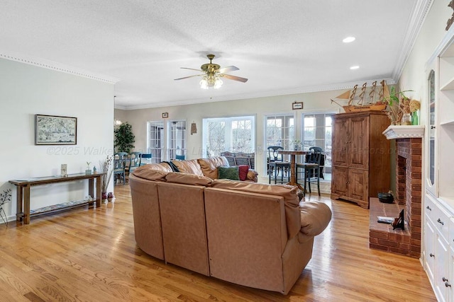 living room with ceiling fan, recessed lighting, a fireplace, light wood-style floors, and crown molding