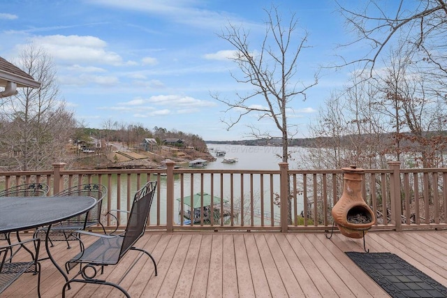 wooden terrace featuring a water view and outdoor dining area