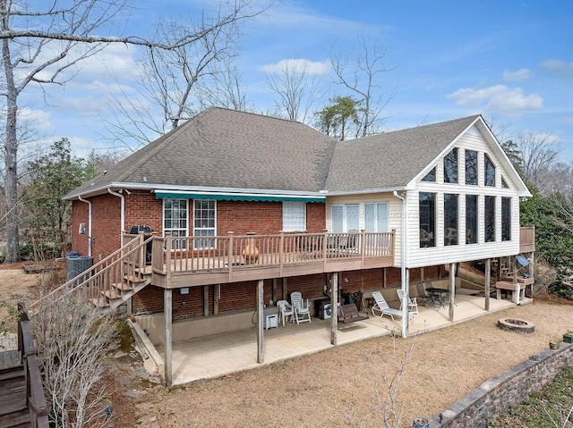 back of property with central air condition unit, a shingled roof, stairway, and a patio