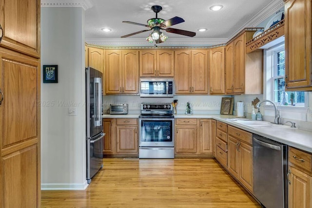 kitchen with appliances with stainless steel finishes, light wood-type flooring, light countertops, and a sink