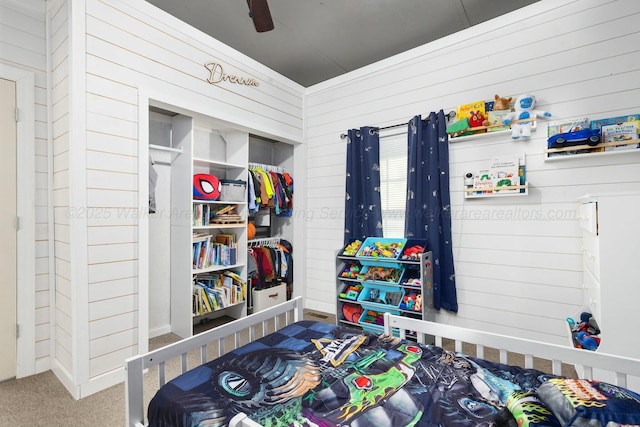 carpeted bedroom with ceiling fan and wood walls