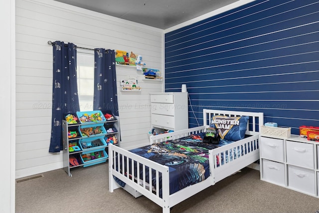 bedroom featuring carpet flooring and wooden walls