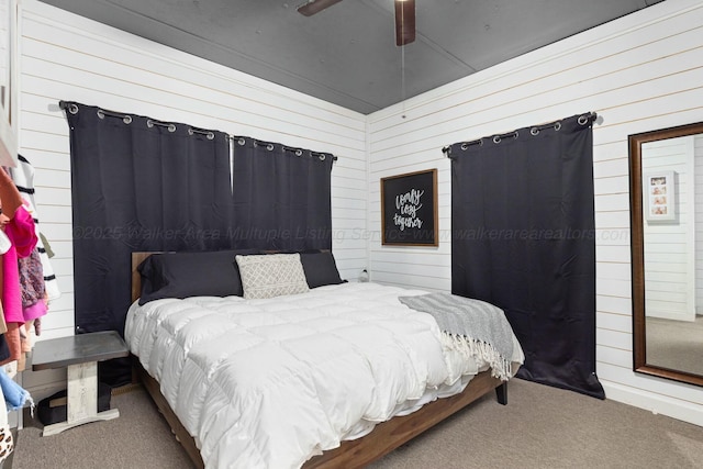 carpeted bedroom with ceiling fan and wood walls