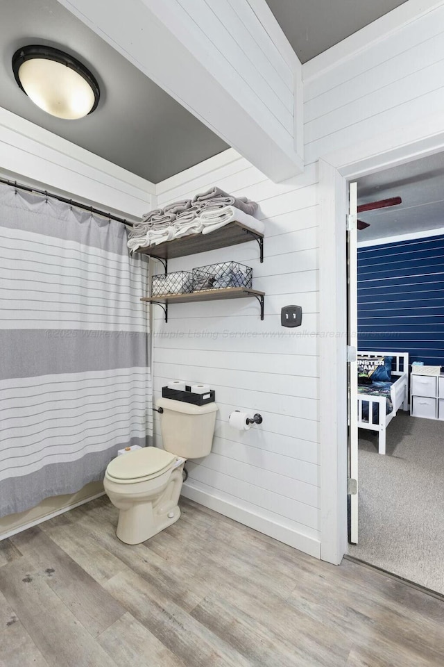 bathroom with hardwood / wood-style floors, curtained shower, and toilet