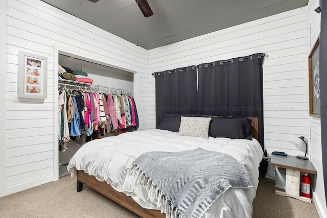 bedroom featuring ceiling fan, carpet floors, a closet, and wood walls