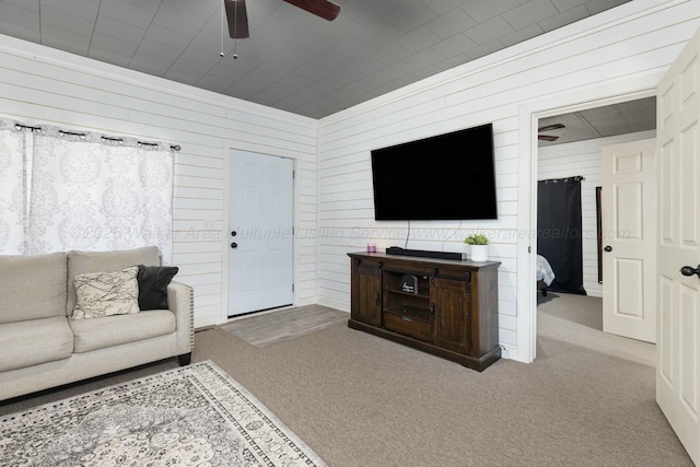 living room with light colored carpet, ceiling fan, and wood walls