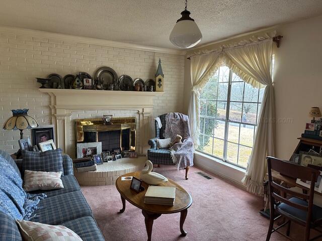 carpeted living room with a fireplace, ornamental molding, a textured ceiling, and brick wall