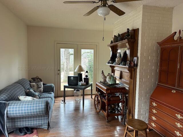 sitting room featuring hardwood / wood-style floors, ceiling fan, and a brick fireplace