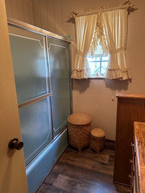 bathroom featuring enclosed tub / shower combo, wood-type flooring, and vanity