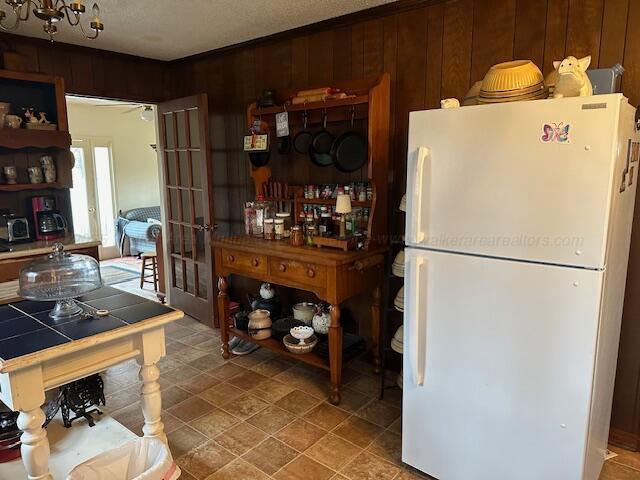 kitchen featuring tile counters, wood walls, and white refrigerator