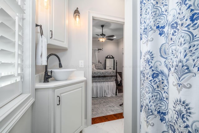 bathroom featuring walk in shower, ornamental molding, vanity, ceiling fan, and wood-type flooring