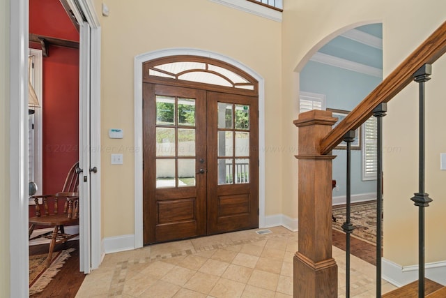 foyer entrance featuring french doors, light hardwood / wood-style flooring, and crown molding