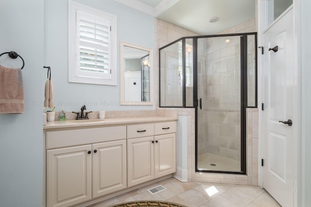 bathroom with tile patterned flooring, vanity, and walk in shower