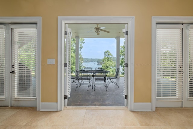 doorway to outside with plenty of natural light, ceiling fan, a water view, and light tile patterned floors