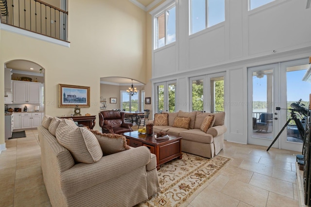 living room featuring a chandelier, a high ceiling, french doors, and ornamental molding