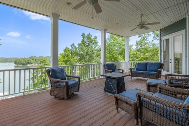 wooden terrace with outdoor lounge area, ceiling fan, and a water view