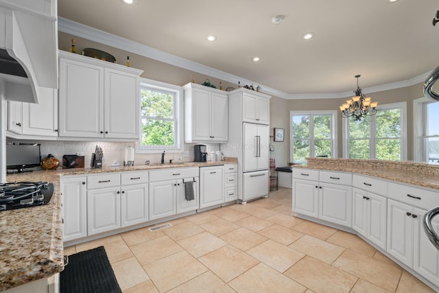 kitchen featuring white cabinets, white built in fridge, decorative backsplash, and hanging light fixtures