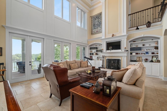 living room with a high ceiling, built in features, french doors, and crown molding