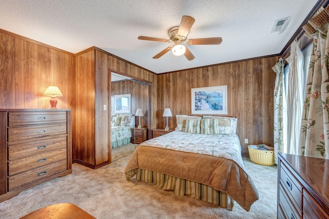 bedroom with crown molding, wooden walls, light carpet, and a textured ceiling