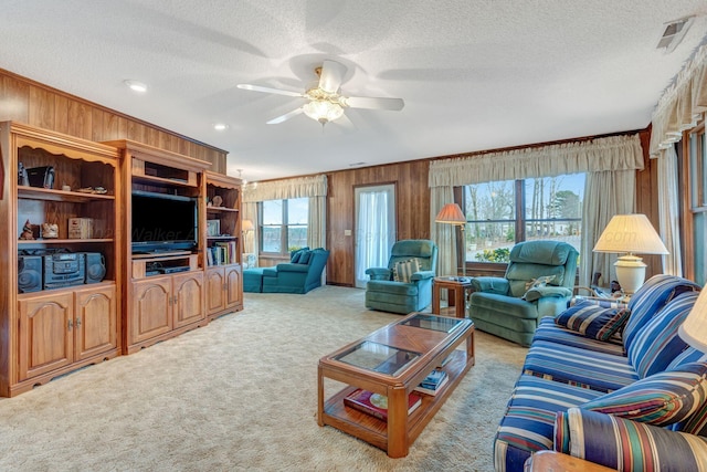 carpeted living room with plenty of natural light, a textured ceiling, and wood walls