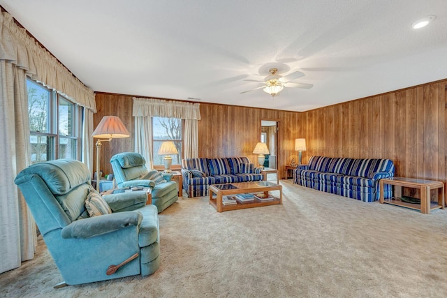 carpeted living room with ceiling fan and wooden walls