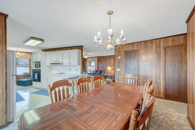 dining area featuring ornamental molding, a textured ceiling, a notable chandelier, and wooden walls