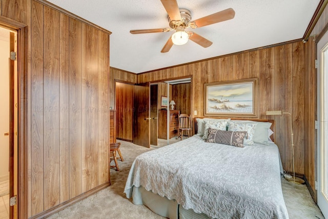 bedroom featuring wooden walls, ornamental molding, light colored carpet, ceiling fan, and a textured ceiling