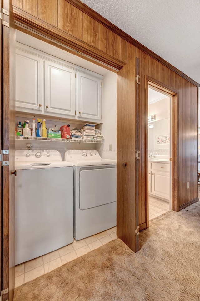 clothes washing area with wood walls, separate washer and dryer, cabinets, ornamental molding, and light carpet