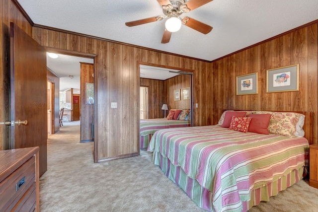 carpeted bedroom featuring ornamental molding, ceiling fan, a textured ceiling, and wood walls