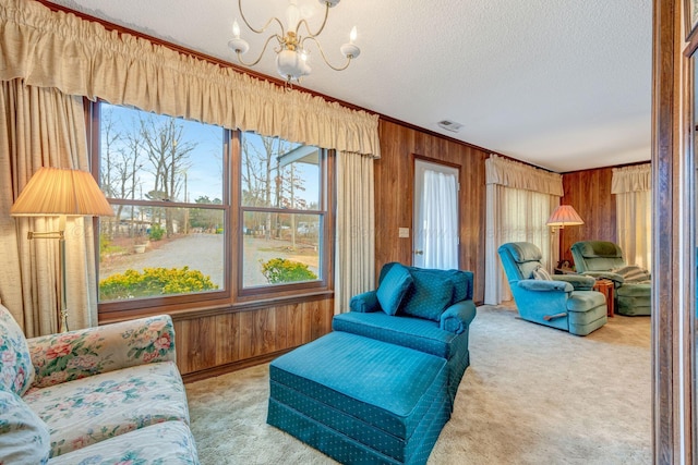 carpeted living room with an inviting chandelier, a textured ceiling, and wood walls