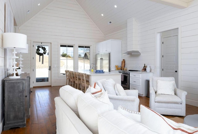 living room featuring dark wood-type flooring, wooden walls, and high vaulted ceiling