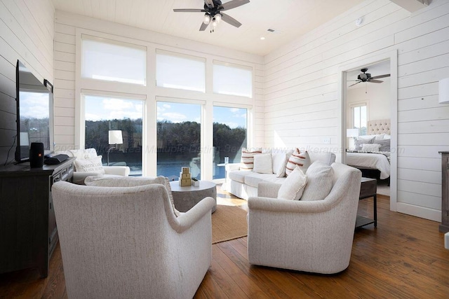 living room featuring a water view, wooden walls, dark hardwood / wood-style floors, and a towering ceiling