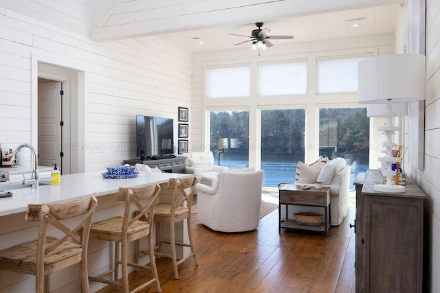 living room featuring high vaulted ceiling, wood walls, sink, dark hardwood / wood-style flooring, and ceiling fan