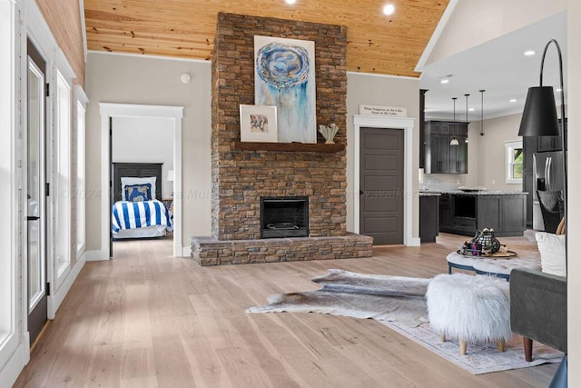 living room with high vaulted ceiling, light hardwood / wood-style flooring, wood ceiling, and a stone fireplace