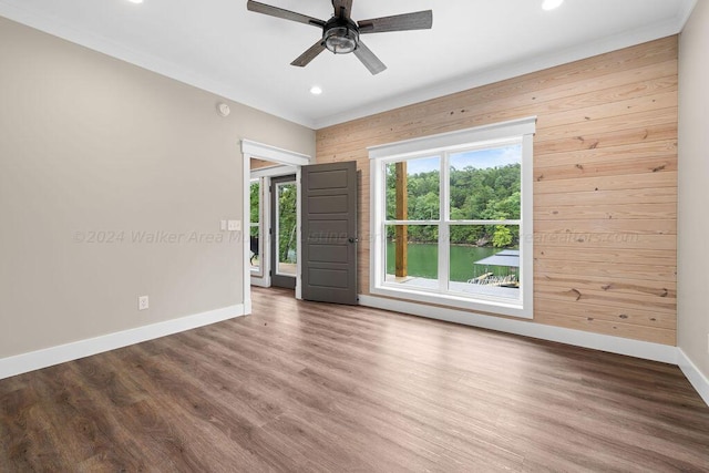 empty room featuring hardwood / wood-style flooring, wood walls, and ceiling fan