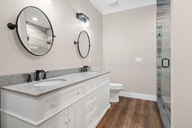 bathroom featuring toilet, wood-type flooring, a shower with door, crown molding, and vanity