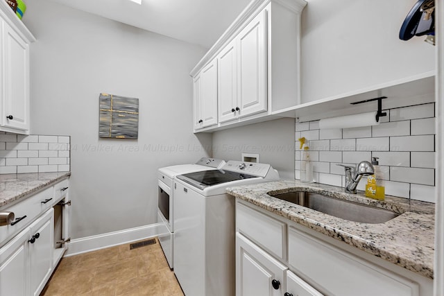 clothes washing area with sink, light tile patterned floors, cabinets, and washing machine and clothes dryer